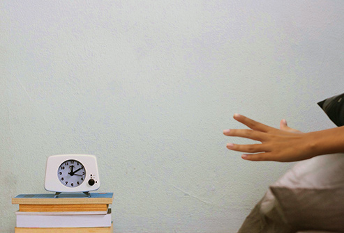 493_getty_rf_woman_reaching_for_alarm_clock